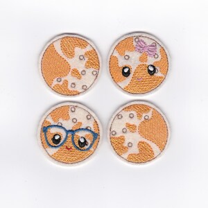 Puede incluir: Cuatro parches bordados para planchar con caras de dibujos animados lindas sobre un fondo blanco con lunares naranja y blancos. Los parches son redondos y tienen un contorno blanco. Un parche tiene un lazo rosa, uno tiene gafas azules y dos no tienen accesorios.