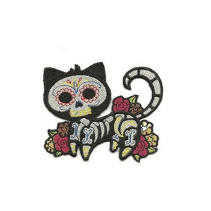 May include: Embroidered iron-on patch of a black cat with a sugar skull face, wearing a skeleton costume and surrounded by colorful flowers.