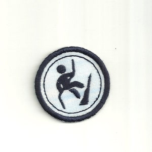 May include: A blue and white embroidered patch with a silhouette of a person climbing a rock wall.