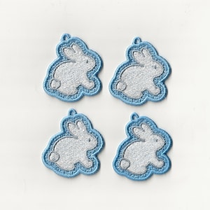 Op de afbeelding: Vier witte geborduurde konijnenpatches met blauwe randen. De konijnen kijken naar de rechterkant van de afbeelding.