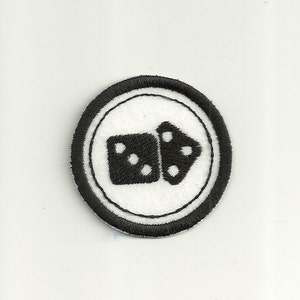 May include: Black and white embroidered patch with a dice design. The dice are in a circle with a black border.