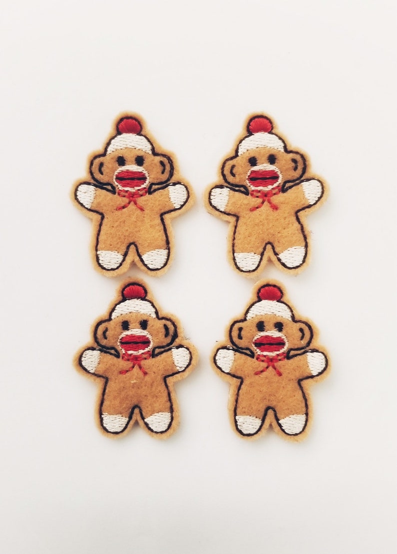 May include: Four felt monkey gingerbread man ornaments with red hats, red mouths, and white trim.