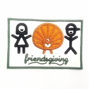May include: An embroidered patch with a green border, featuring two stick figures, one female and one male, standing on either side of a stylized orange turkey. The text "friendsgiving" is written in cursive below the figures.