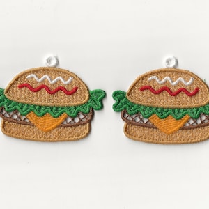 May include: Two embroidered patches of a hamburger with lettuce, cheese, tomato, and a white bun.