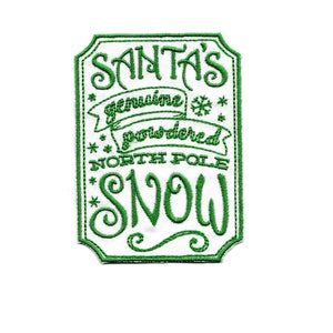 Pode incluir: Etiqueta bordada verde com texto branco que diz "Santa's genuine powdered North Pole snow".