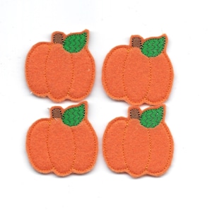 Puede incluir: Cuatro calabazas de fieltro naranja con hojas verdes y tallos marrones. Las calabazas tienen un diámetro de aproximadamente 5 cm.