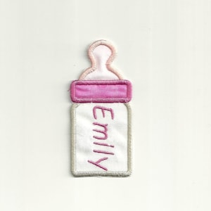 May include: White baby bottle with a pink lid and a pink embroidered name "Emily" on the front.