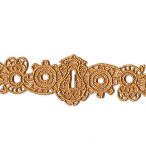 May include: Gold-colored metal trim with a keyhole design. The trim has a decorative, intricate pattern with multiple circles and swirls.