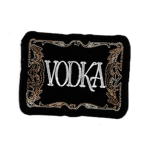 Könnte beinhalten: Schwarzer gestickter Aufnäher mit einem goldenen verzierten Rahmen und dem Wort "VODKA" in weißen Buchstaben.