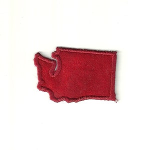 May include: A red felt patch in the shape of the state of Washington. The patch has a white outline.