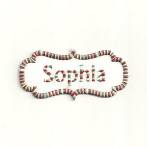 May include: White embroidered name tag with a red and green striped border. The name "Sophia" is embroidered in white on the tag.