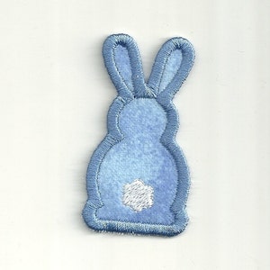 May include: A light blue felt bunny applique with a white felt tail. This embroidered patch is perfect for adding a touch of whimsy to crafts and projects.