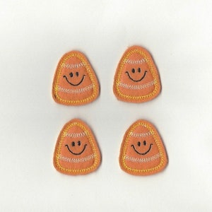 Puede incluir: Cuatro parches de maíz dulce de fieltro naranja con un contorno amarillo y una carita sonriente negra.