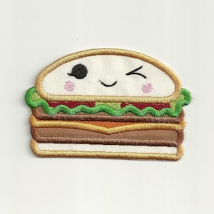 May include: A white, brown, and green embroidered patch of a cartoon burger with a winking face.
