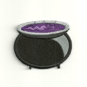 May include: A black cauldron with a purple liquid inside. The cauldron has a silver rim and three legs.