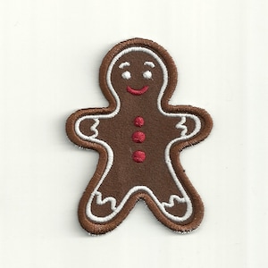 May include: A brown gingerbread man cookie with white icing and red buttons. The gingerbread man is smiling with white eyes and a white mouth.