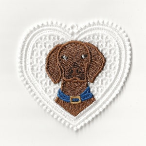 May include: Embroidered brown dog with a blue collar, inside a white heart-shaped lace frame.