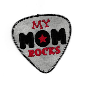 May include: A gray guitar pick shaped patch with black and red embroidery. The text "MY MOM ROCKS" is embroidered on the patch with a red star in a black circle.