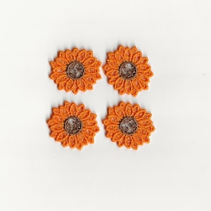 May include: Four orange lace sunflower appliques with brown centers.