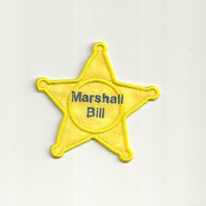 May include: Yellow five-pointed star shaped badge with a blue circle in the center that says "Marshall Bill".