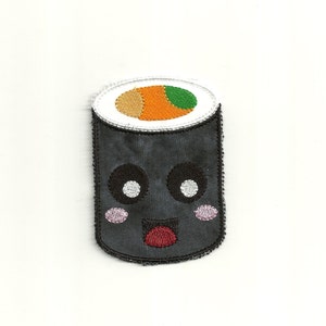 May include: A black and white embroidered sushi roll with a smiling face. The sushi roll has a green, orange, and brown filling.
