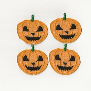 May include: Four orange felt pumpkin patches with black embroidered jack-o'-lantern faces.