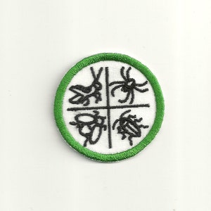 Op de afbeelding: Een witte geborduurde patch met een groene rand. De patch heeft vier zwart-witte illustraties van insecten: een sprinkhaan, een spin, een kever en een lieveheersbeestje.