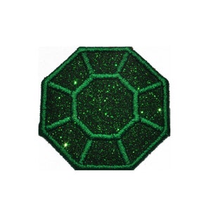 Puede incluir: Un parche verde brillante en forma de diamante con un contorno verde oscuro.