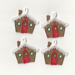 Może przedstawiać: Cztery brązowe ozdoby w kształcie domku z piernika z białym lukrem, czerwonymi drzwiami i zielonymi wieńcami. Ozdoby mają pętelkę do zawieszenia.
