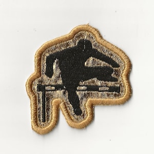 May include: Embroidered patch featuring a black silhouette of a person jumping over a hurdle. The patch has a gold border and gold stitching around the hurdle and the person. The patch is on a white background.