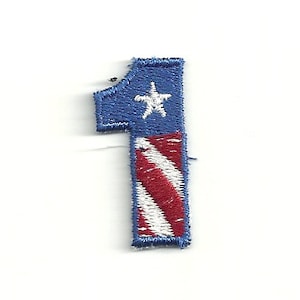 Puede incluir: Un parche bordado con forma de número uno, en azul y rojo con una estrella blanca en la parte superior del número. El parche tiene un patrón de rayas rojas y blancas en la parte inferior del número.