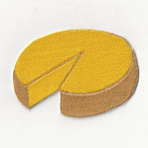 Op de afbeelding: Geborduurde patch met een gele taart waarvan een stuk ontbreekt. De taart heeft een bruine korst en een getextureerde afwerking. Geschikt voor kleding of accessoires.