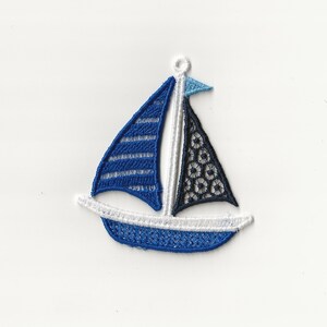 Puede incluir: Un velero azul y blanco con una vela de encaje negro, bordada con un contorno blanco. El velero es un adorno decorativo.