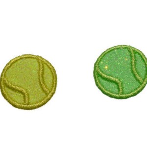 Puede incluir: Dos parches en forma de pelota de tenis de color verde y amarillo con una costura blanca. Los parches están hechos de una tela brillante.