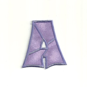 May include: Purple felt letter A with a white outline. The letter is in a stylized font.
