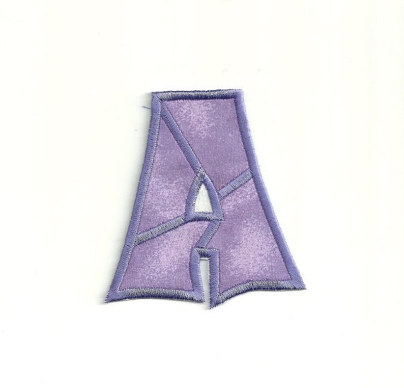May include: Purple felt letter A with a white outline. The letter is in a stylised font.