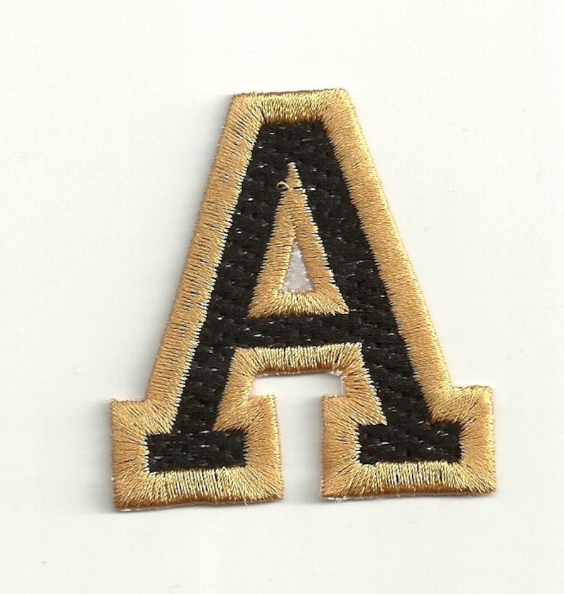 以下が含まれることがあります： 金色の縁取りが付いた黒いフェルトの文字A。文字は刺繍されており、ビンテージな外観です。
