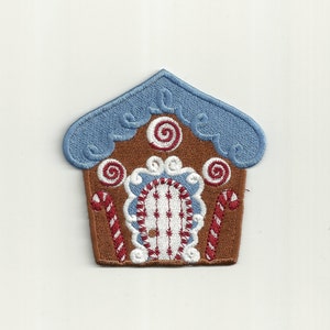 May include: A brown gingerbread house with a blue roof, white frosting, and red candy canes. The house has a white door with red stripes and a white and red candy cane design.