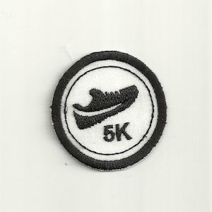 Puede incluir: Un parche bordado en blanco y negro con un diseño de zapatilla para correr y el texto "5K".