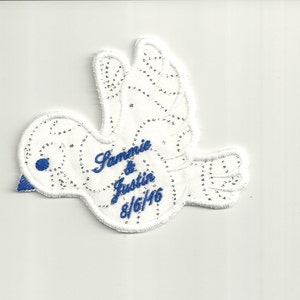 May include: White dove with blue embroidered details, featuring the names "Sammie & Justin" and the date "8/6/46".