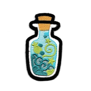 Puede incluir: Un parche bordado de una botella de vidrio azul con un tapón de corcho. La botella está llena de un líquido azul que gira con acentos verdes y amarillos.