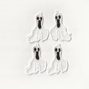 May include: Four white felt ghost ornaments with black embroidered eyes and mouths. The ghosts are hanging from a white background.