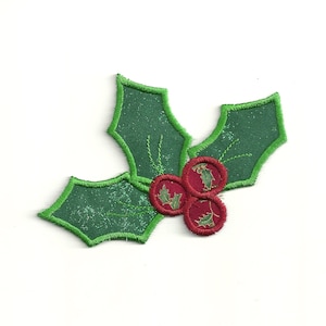 May include: A green felt holly leaf with three red felt berries. The berries have a small green felt holly leaf design on them.
