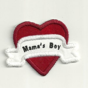 Puede incluir: Corazón de fieltro rojo con una pancarta bordada en blanco que dice "Mama's Boy".
