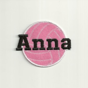 May include: Pink volleyball with white stitching and the name "Anna" embroidered in black.