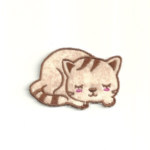 Op de afbeelding: Een geborduurde patch van een slapende kat, met bruine en witte kleuren. De kat heeft gesloten ogen, een bruine neus en roze wangen.
