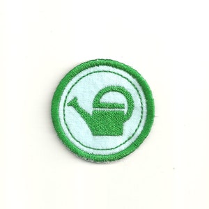 May include: Green embroidered patch with a white outline. The patch features a green watering can with a white handle and spout.