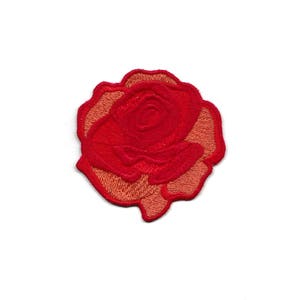 Puede incluir: Un parche bordado de rosa roja con un contorno rosa claro. La rosa es un diseño floral clásico.