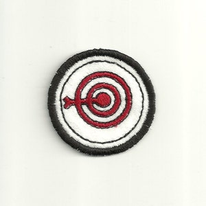 May include: A red and white embroidered target with a black border. The target has three concentric circles and a red bullseye.