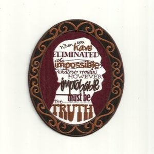 Könnte beinhalten: Ein braunes und schwarzes gesticktes Patch mit einem Zitat, das lautet: "Wenn du das Unmögliche eliminiert hast, ist das, was übrig bleibt, so unwahrscheinlich es auch sein mag, die Wahrheit."